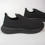 Tênis slip-on preto de malha respirável, com sola grossa e design casual para conforto diário.